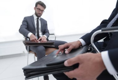 Klasik elbiseli adam kahverengi çanta yakın tutar