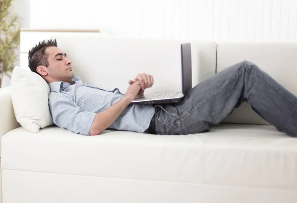 Man met laptop liggend op de Bank — Stockfoto