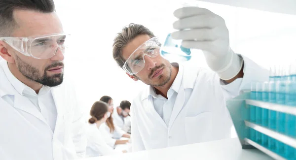Closeup. scientist and assistant studying the solution in the glass tube — Stock Photo, Image