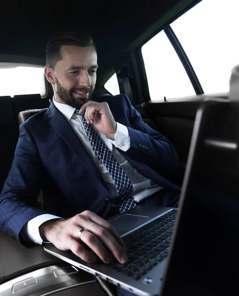 Podnikatel přečte informace o notebooku, zatímco sedí v autě — Stock fotografie