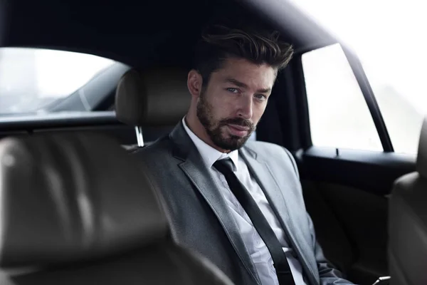 Бізнесмен в елегантному костюмі на задньому сидінні автомобіля — стокове фото