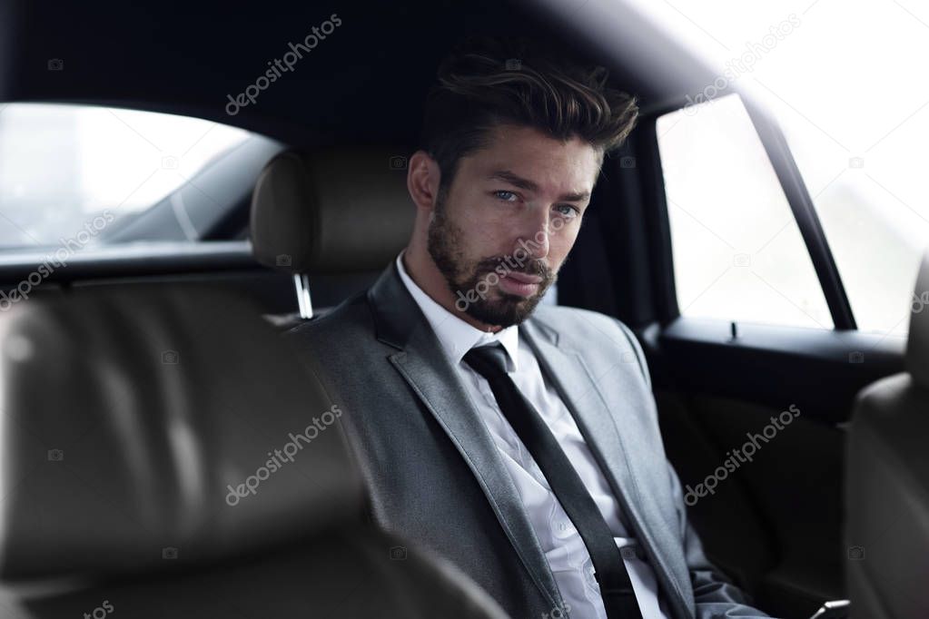 Businessman in elegant suit on backseat of car