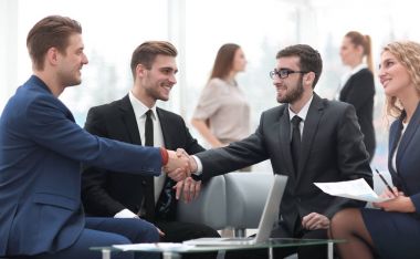 Ortaklar, takım üyelerinin huzurunda anlaşma yapıp el sıkışıyorlar.