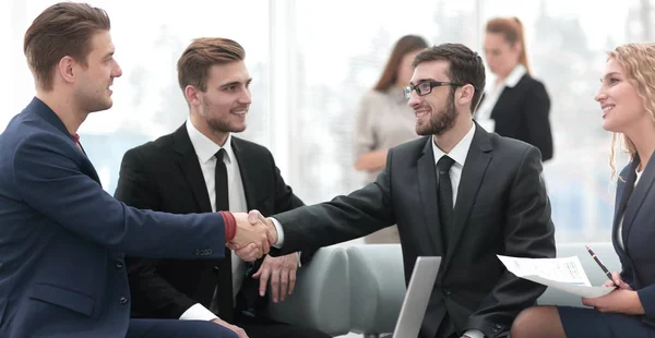 Partner bei Vertragsabschluss und Händeschütteln im Beisein von Teammitgliedern — Stockfoto