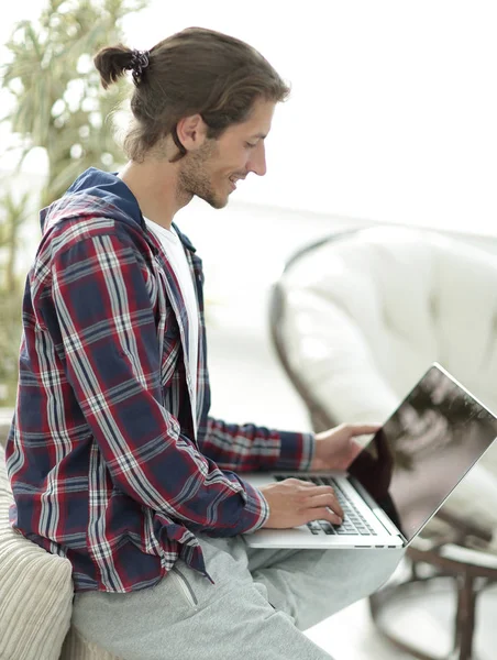 Élégant jeune homme travaillant sur ordinateur portable et regardant la caméra — Photo