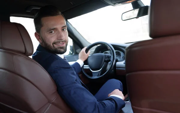 businessman sitting at the wheel of a prestigious car