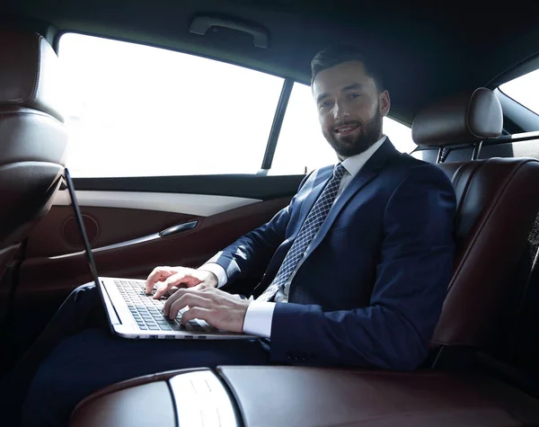 Junge Geschäftsfrau arbeitet an ihrem Laptop, während sie im Auto sitzt — Stockfoto