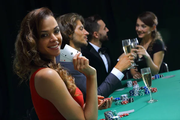 Young brunette woman playing poker on black background — Stock Photo, Image