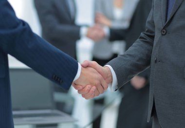 İş ortakları iş yerlerindeki iş eşyalarının üzerinden el sıkışıyor