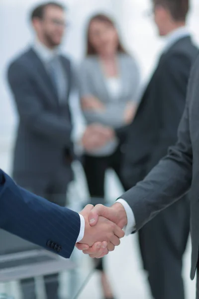 Dois homens de negócios apertando as mãos com colegas em segundo plano. — Fotografia de Stock