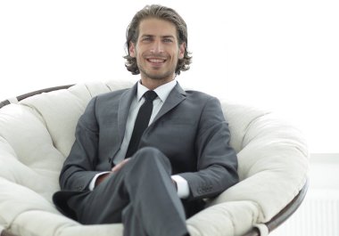 Kendine güvenen işadamı büyük bir rahat sandalyede oturuyor.