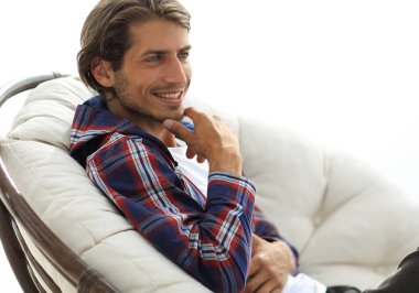 yakın çekim. gülümseyen adam büyük bir rahat sandalyede dinleniyor