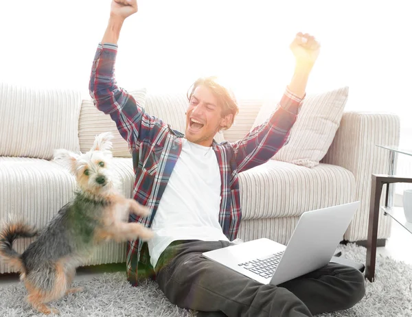 Mutlu genç adam köpeğiyle oturma odasında exults — Stok fotoğraf