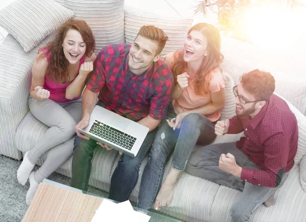 Triumphierende Gruppe von Freunden lacht, während sie auf der Couch im Wohnzimmer sitzt — Stockfoto