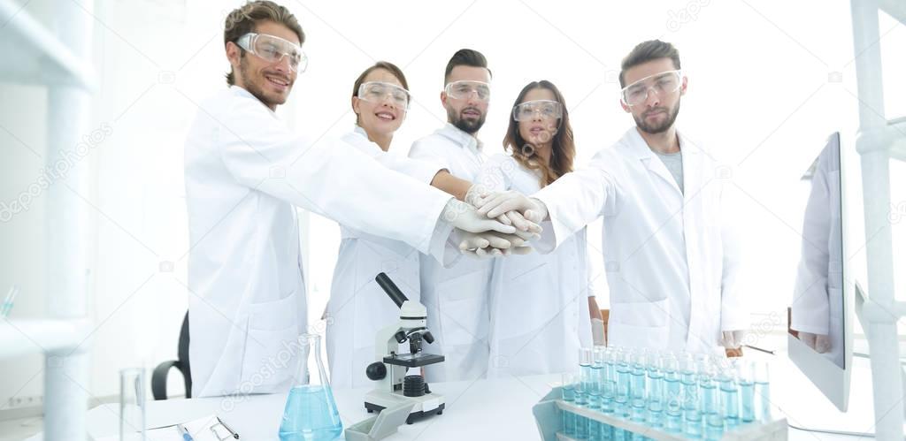 successful team of young scientists with hands clasped together.