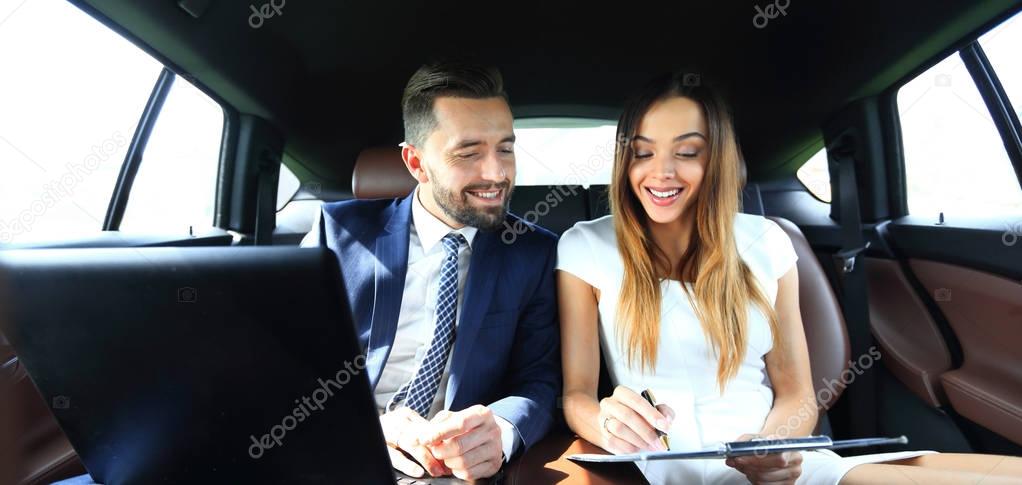 man and woman discussing work documents in taxi
