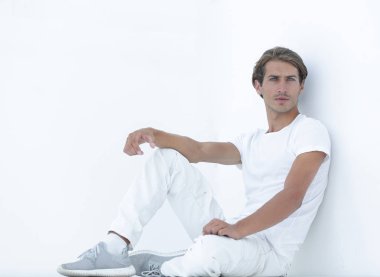 Beyaz bir duvar oturan üzgün genç adam