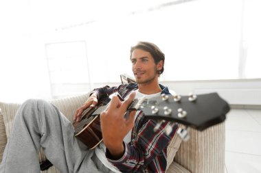 gitar oturma odasında kanepede oturan adam. bir yaşam tarzı kavramı