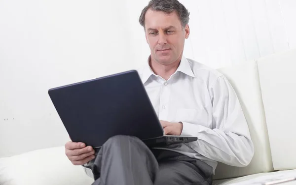 Homem de negócios bem sucedido trabalhando no laptop sentado no sofá — Fotografia de Stock