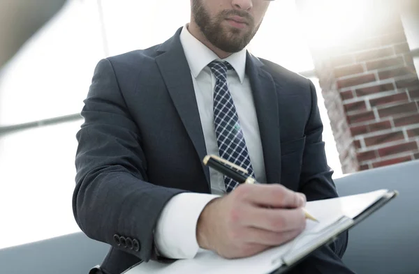 Affärsman som skriver i en anteckningsbok i ett kontor — Stockfoto