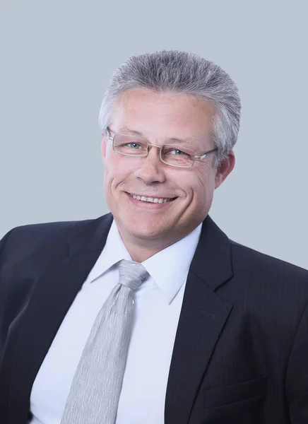 Portrait of smiling senior businessman standing against gray — Stock Photo, Image