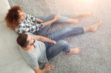 yeni bir oturma odasında bir halı üzerinde oturan yeni evli çift