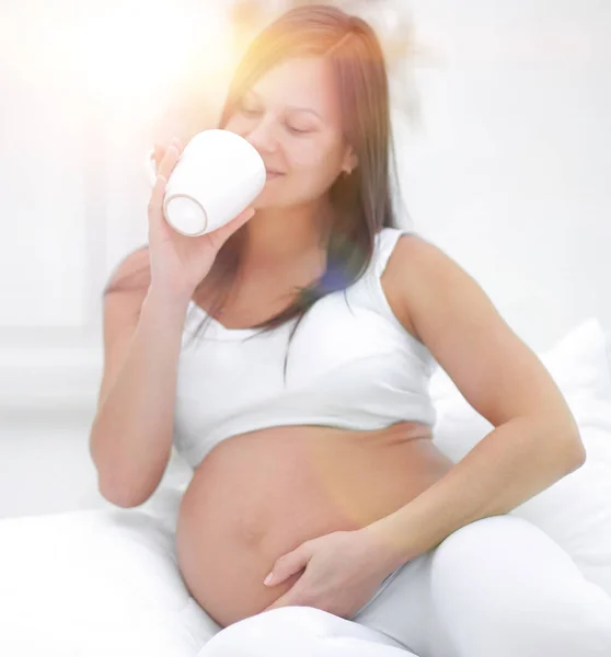 Happy pregnant woman drinking milk sitting in the living room. — Stock Photo, Image