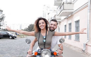 Güzel genç bir çift bir scooter sürme sırasında gülümsüyor