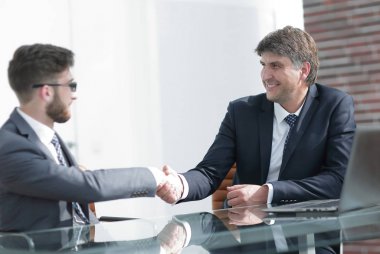 Toplantı sırasında iki iş arkadaşı el sıkışıyor.