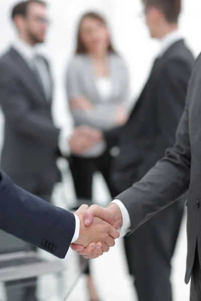 Dos hombres de negocios estrechando la mano con sus colegas de fondo. —  Fotos de Stock
