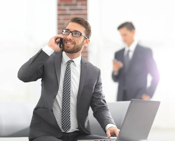 Уверенный молодой человек разговаривает по телефону в офисе — стоковое фото