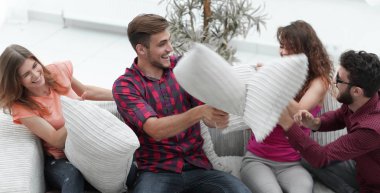 yastık savaşı oynarken, kanepede oturan neşeli arkadaşları