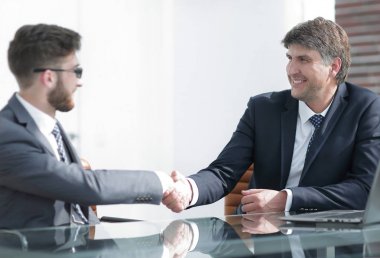 Toplantı sırasında iki iş arkadaşı el sıkışıyor.