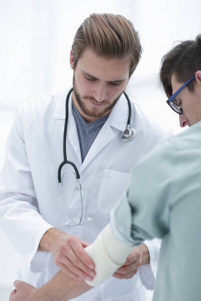 Ортопед накладывает повязку на руку пациента
