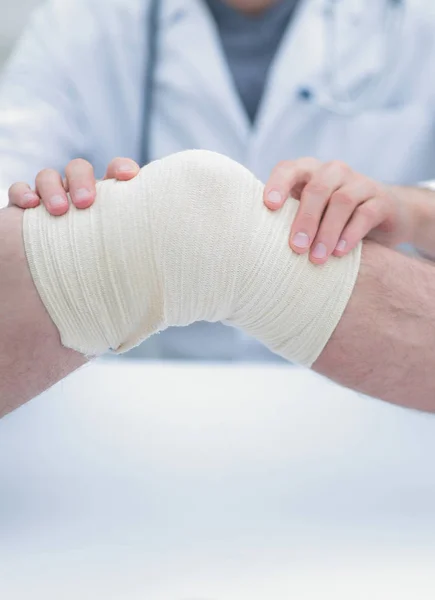 Traumatologista, aplicando uma bandagem no joelho — Fotografia de Stock