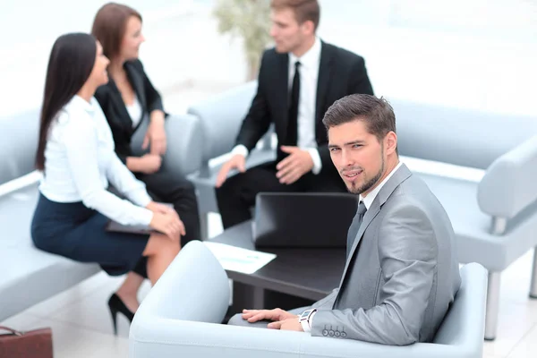 Zakenman zit in een kantoor op de achtergrond van business team. — Stockfoto