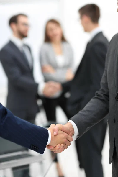 Dos hombres de negocios estrechando la mano con sus colegas de fondo. —  Fotos de Stock