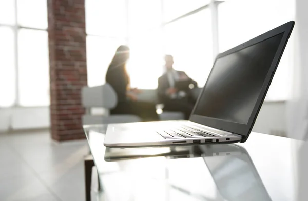 Concéntrate en el portátil sobre la mesa. Personas borrosas en el fondo . — Foto de Stock