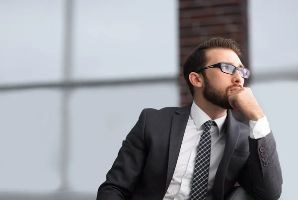 Knappe zakenman denkt, zittend op de bank in zijn kantoor — Stockfoto