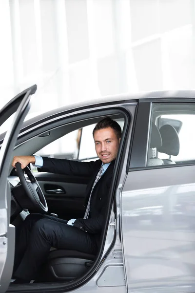 Affärsman som sitter bakom ratten i en bil, på parkeringen på bilfirma — Stockfoto