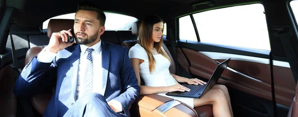 Uomini d'affari che utilizzano telefoni cellulari e laptop durante un viaggio — Foto Stock