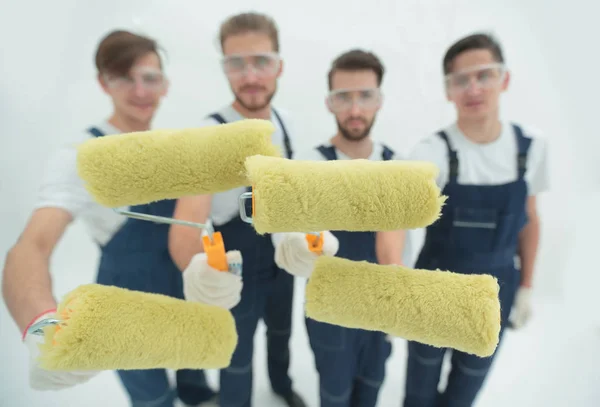 Closeup.a team of builders with paint rollers.i — Stock Photo, Image