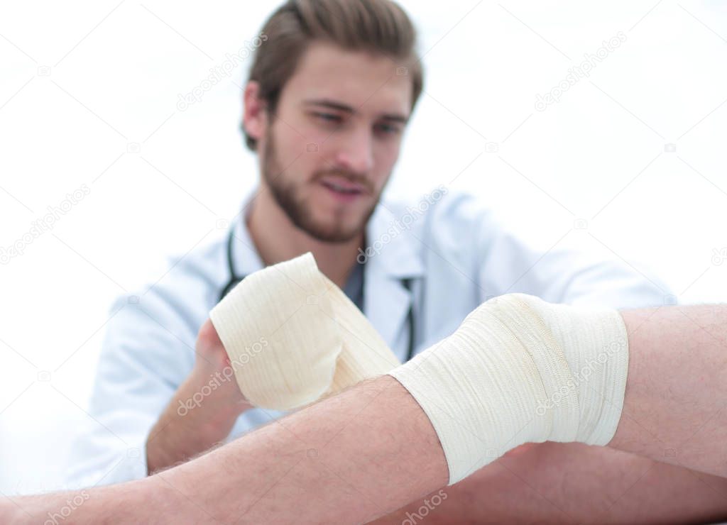 doctor bandaging a wound on the leg of the patient