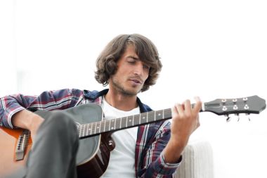 Yakışıklı adam evde kanepede gitar çalmaya