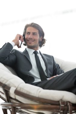 iş adamı rahat bir sandalyede otururken Smartphone'da konuşuyor.