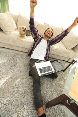 geniş oturma odasında Skordan dizüstü bilgisayar ile mutlu adam.