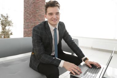 Genç işadamı ofiste dizüstü bilgisayarla çalışıyor.