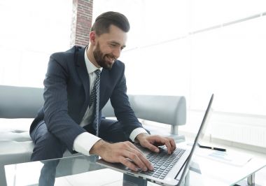Modern ofis dizüstü bilgisayarda çalışan başarılı erkeğin