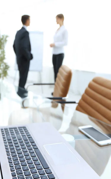 Bärbar dator och en smartphone på skrivbordet i konferensrummet. — Stockfoto