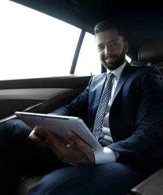 bir arabanın arka koltuğunda çalışma ve bir tablet kullanarak iş adamı